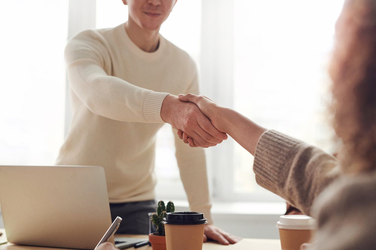 Two people shaking hands over a desk 